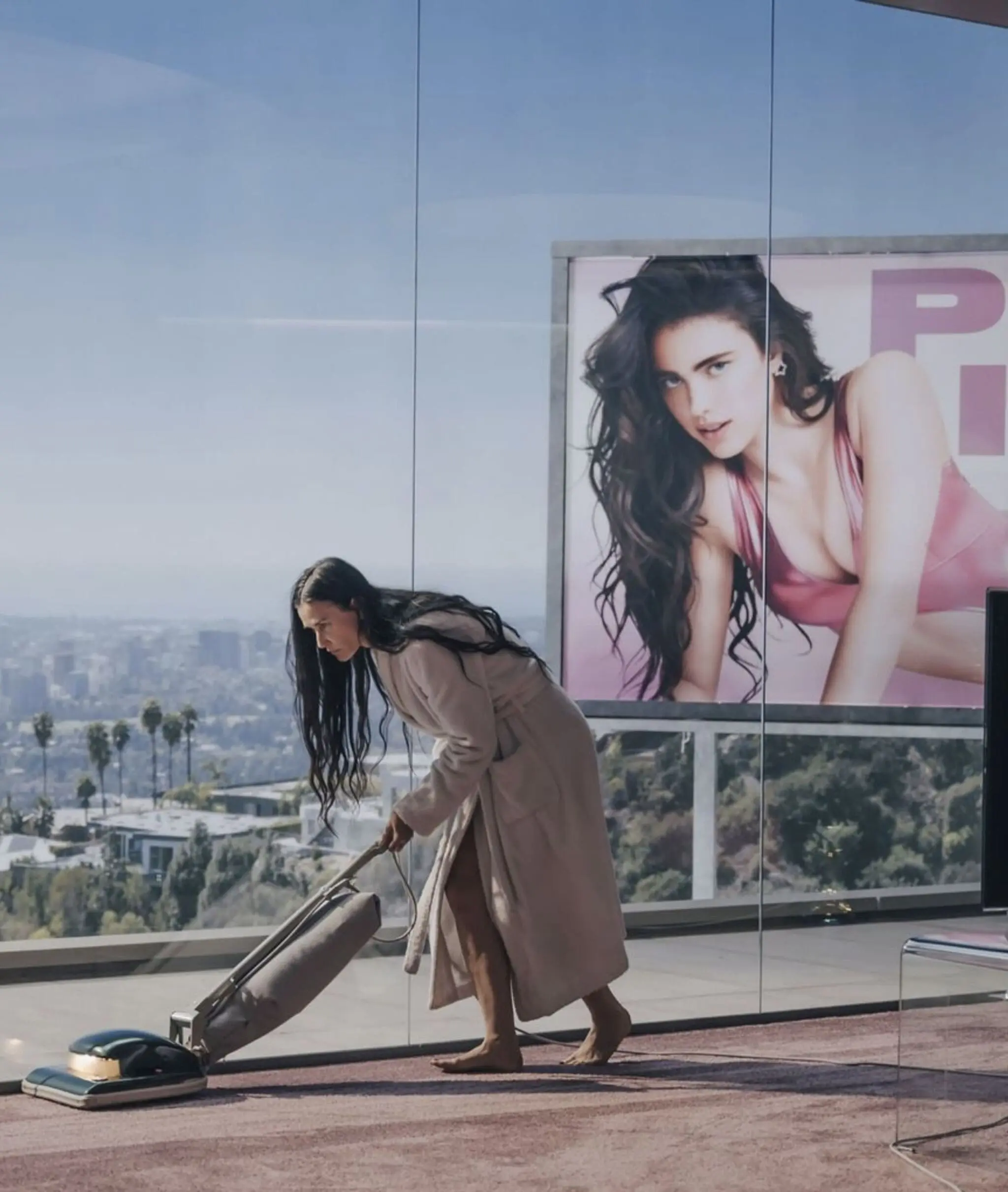Scene from “The Substance” with Demi Moore vacuuming in front of her own billboard.