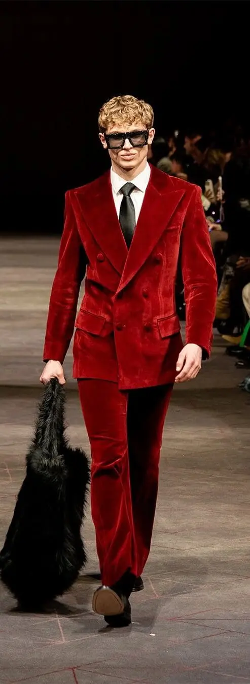 Model in red velvet double-breasted suit and dark sunglasses on the runway