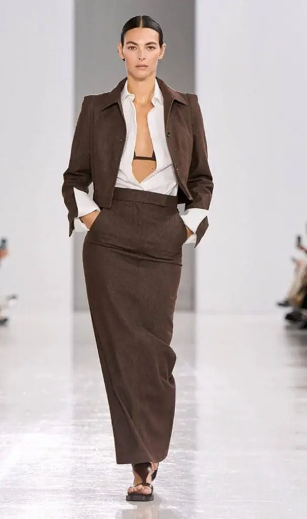 MaxMara model in chocolate brown fitted skirt suit with open blouse