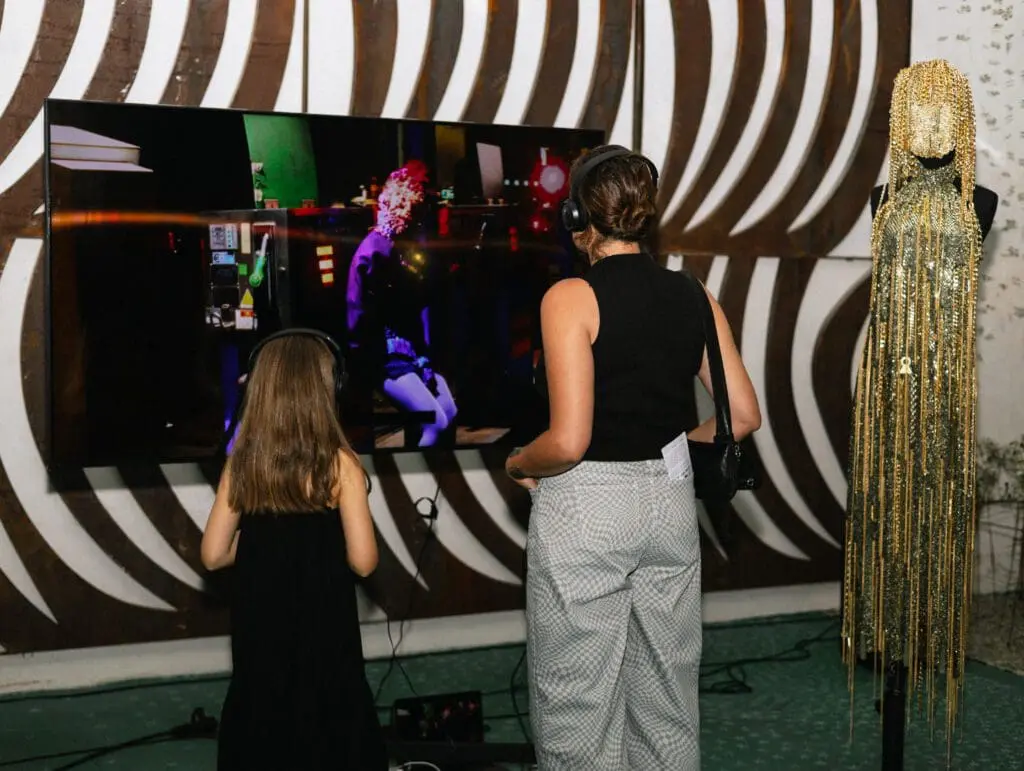 Woman and child watching interactive screen with fashion masks