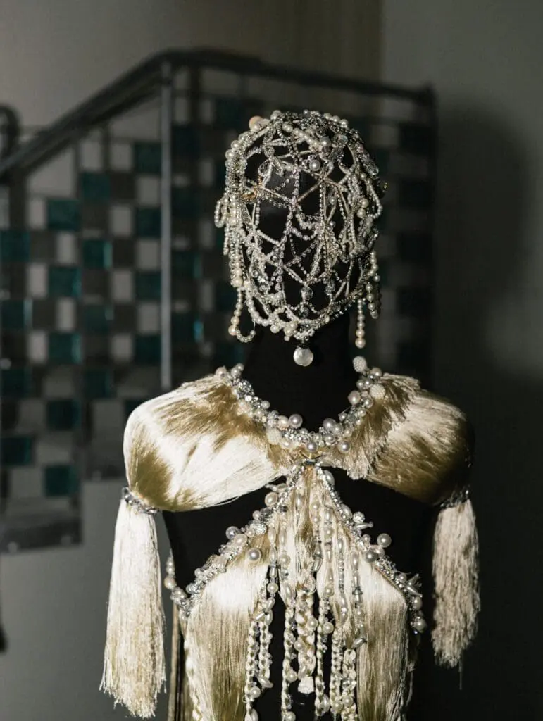 Pearl-beaded mask and gold tassel costume on mannequin