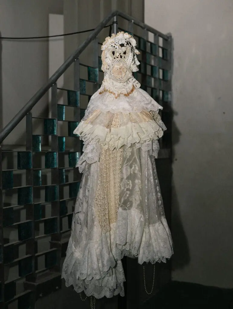 White lace mask and layered costume displayed on mannequin