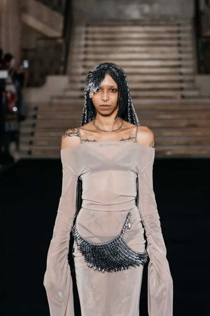 Model in sheer dress with metallic hairpiece and belt