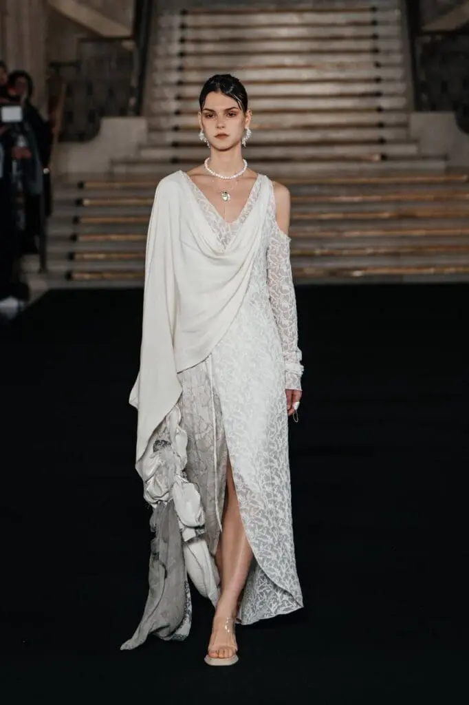 Model in long white gown with tall sculptural headpiece