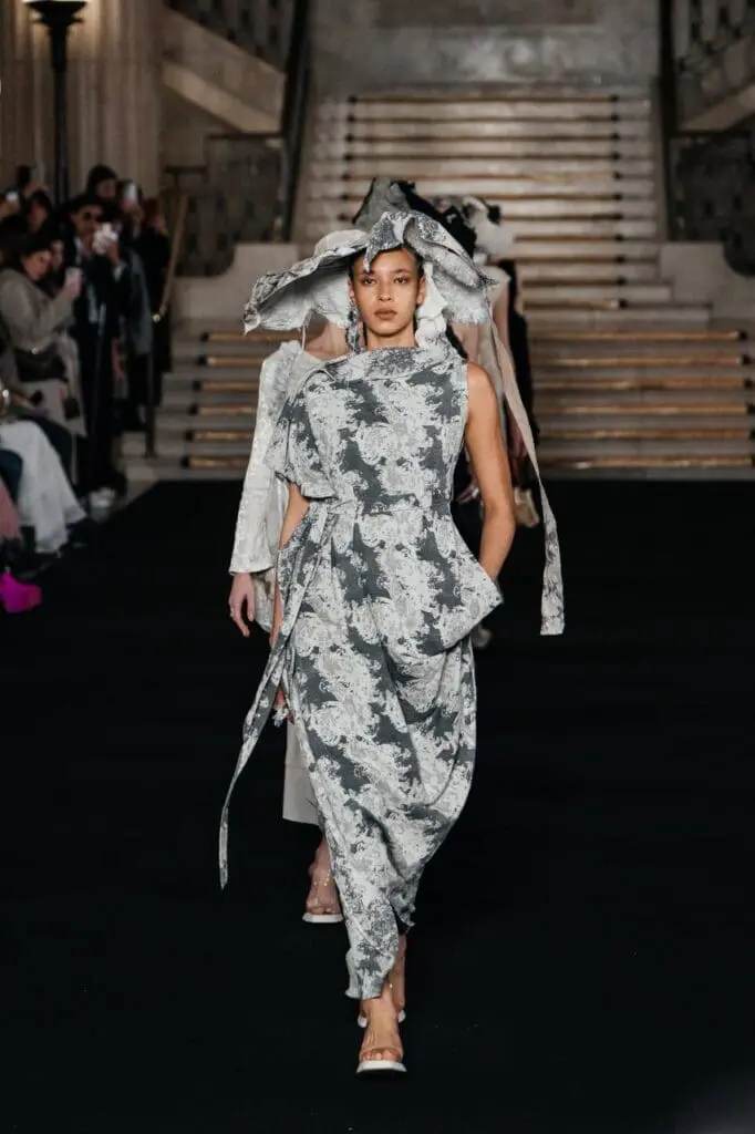 Model in white textured suit with sculptural shoulders