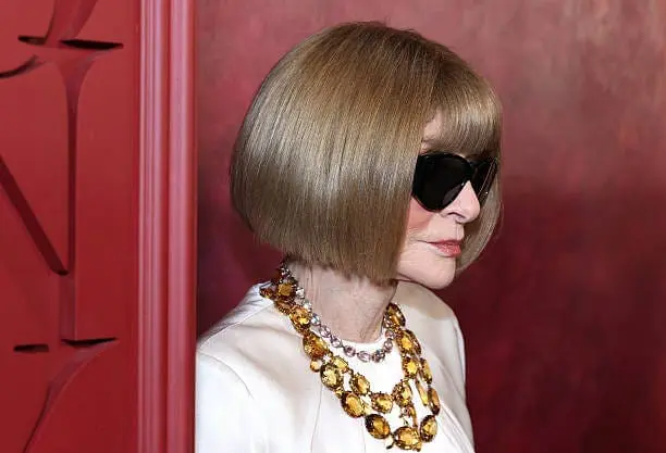 Anna Wintour in sunglasses and a white outfit with yellow gemstone necklace at the 2025 Tony Awards
