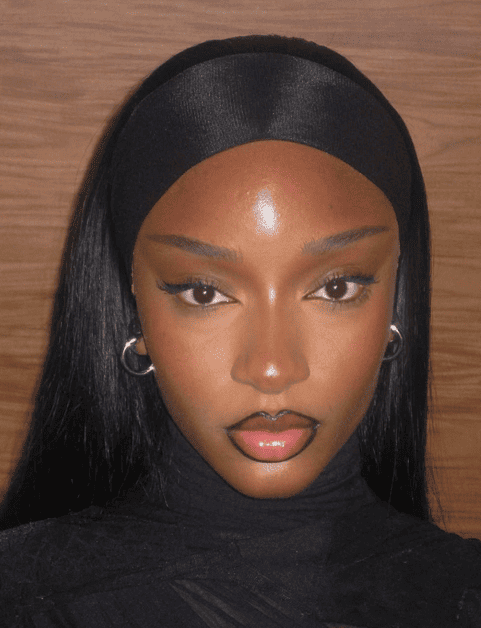 Close-up of Arya Starr in glowing bronze makeup with soft lashes and brown lip