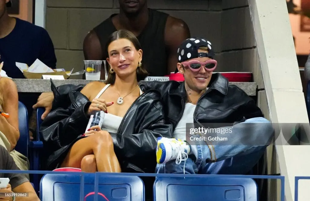 Hailey and Justin Bieber sitting courtside at 2023 US Open, both in black leather jackets