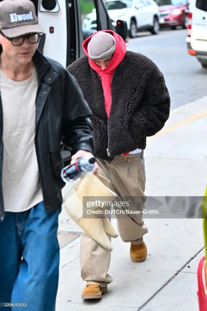 Justin Bieber wearing oversized brown fur jacket and hoodie walking with head down