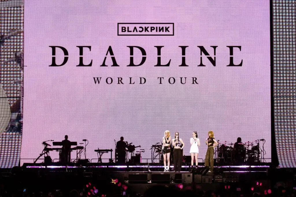 BLACKPINK standing on stage with Deadline Tour screen