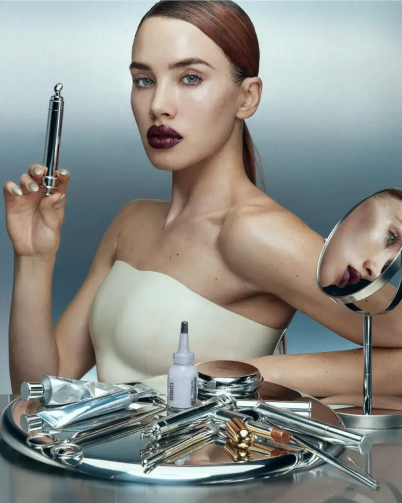 Model holds metallic syringe-shaped tool among futuristic beauty instruments