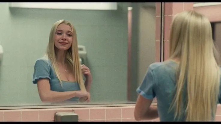 Girl in blue dress crying and smiling at herself in the mirror