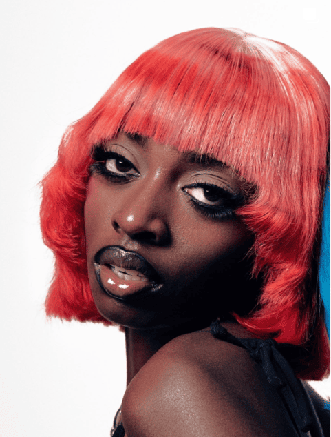 Editorial portrait of Bree Runway in neon red wig with glossy graphic lips