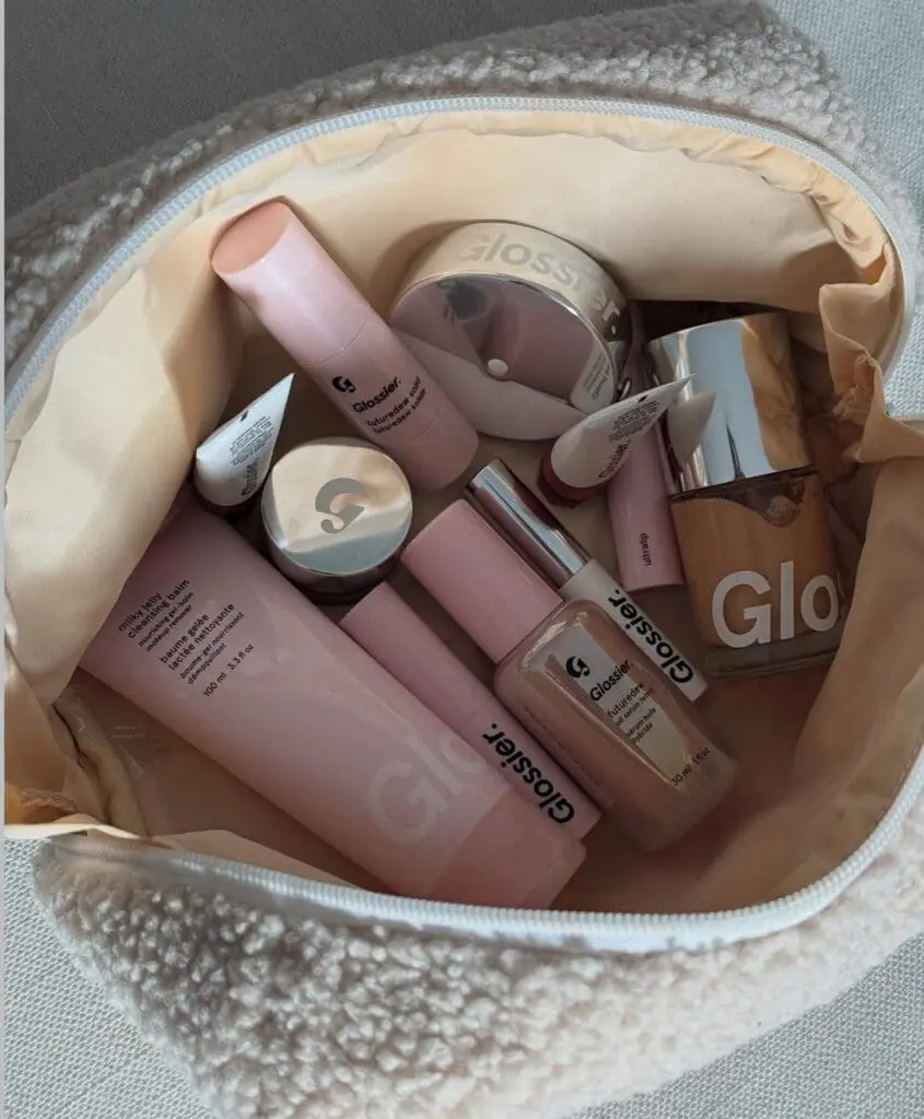A collection of Glossier beauty products in a fleece pouch