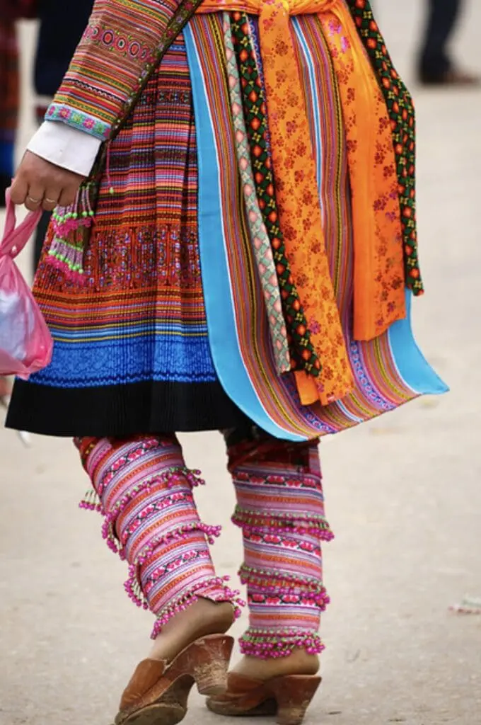 Colorful woven leg wraps and patterned skirt of a Hmong woman
