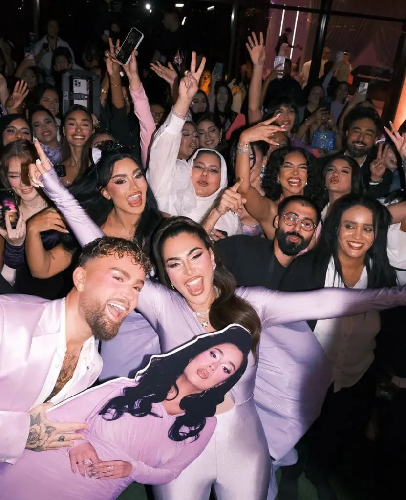 Huda Kattan and fans celebrating with a cutout of herself