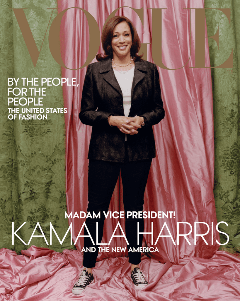 Kamala Harris standing with hands clasped in front of pink satin drape