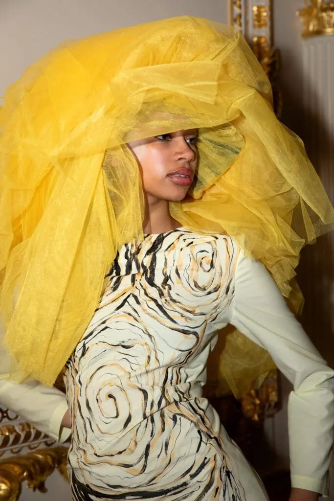 Close-up of model in yellow veil and cream dress with woodgrain print