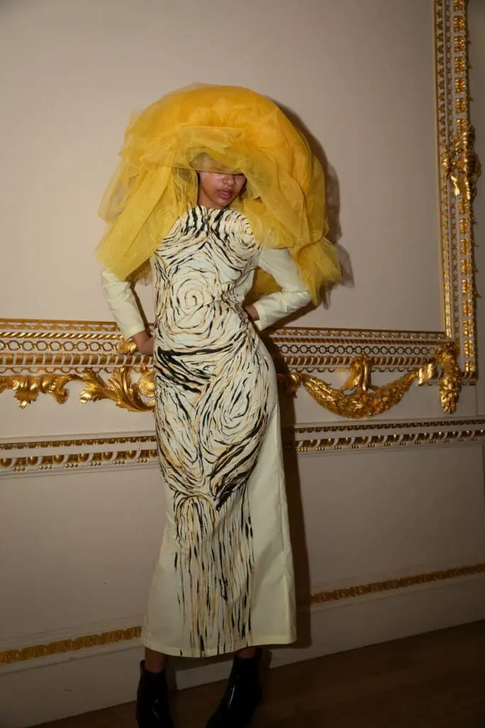 Model in full-length cream dress with woodgrain print and yellow veil