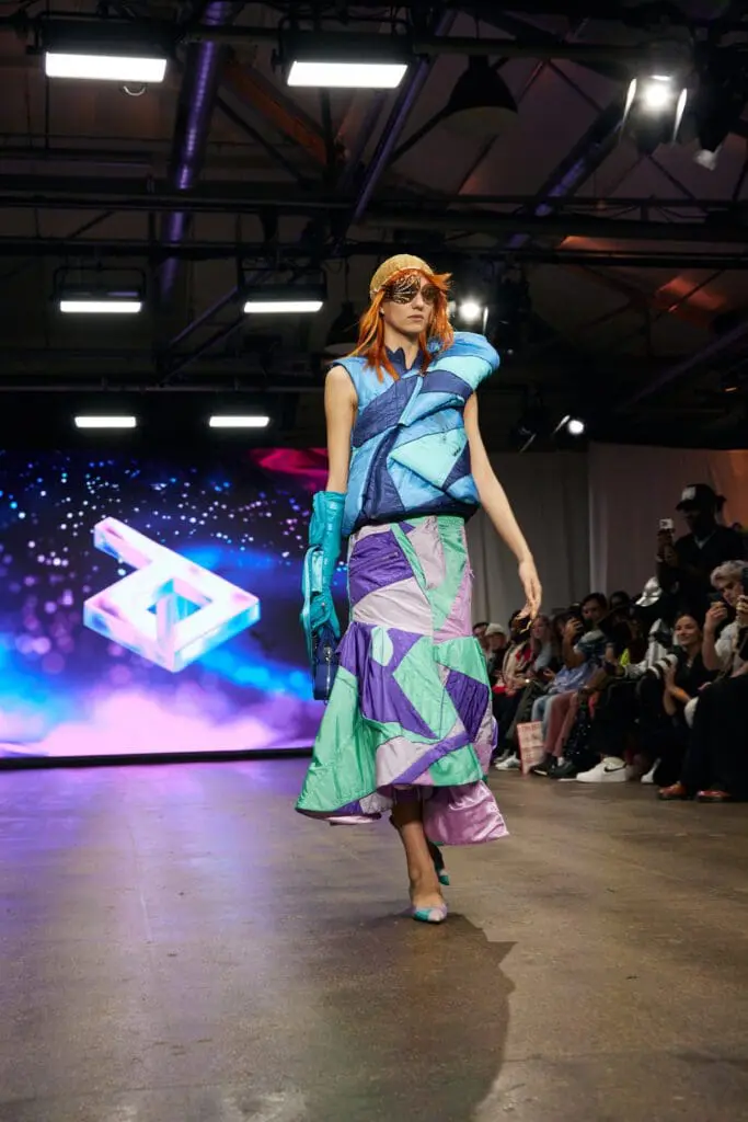 Model in blue and purple patchwork dress on runway