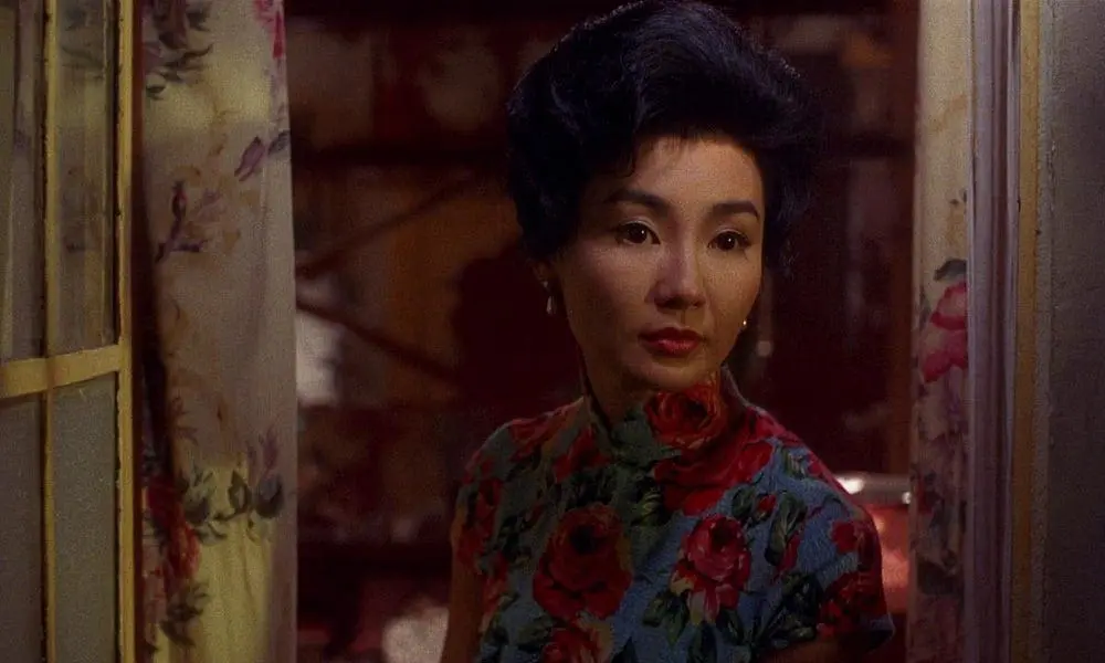 Su Li-zhen stands still in a red floral dress, framed by curtains