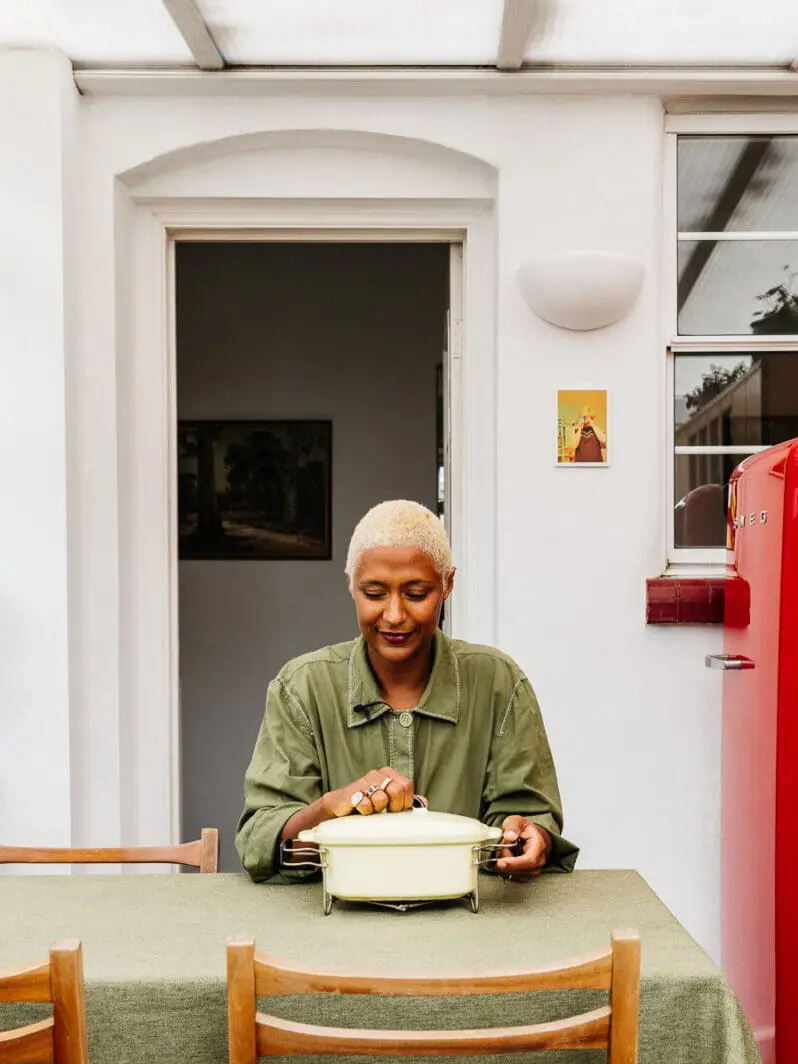 Maya Njie sitting at her dining table in a light-filled kitchen