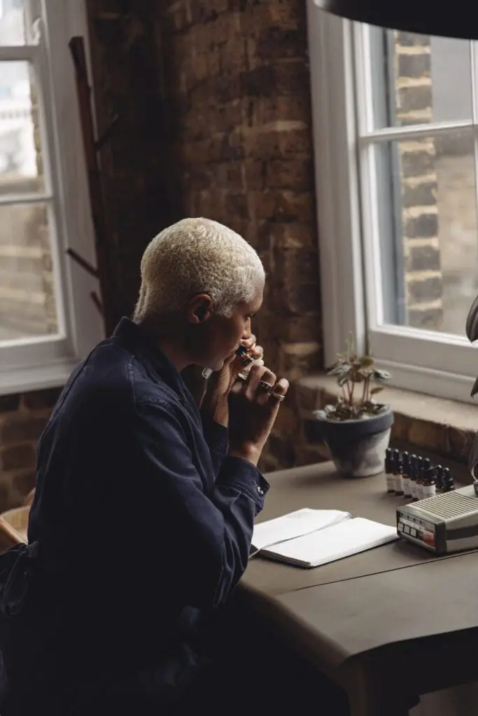 Maya Njie smelling a dropper bottle at her studio desk