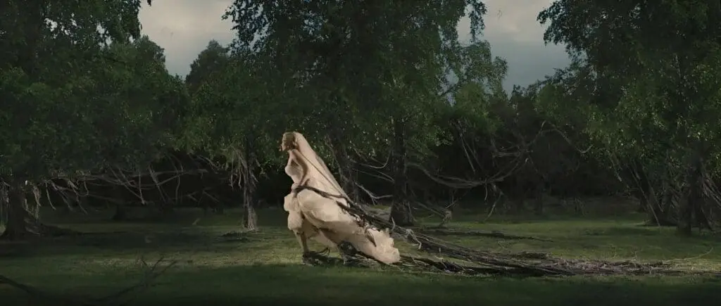 Bride pulling heavy roots through dark forest