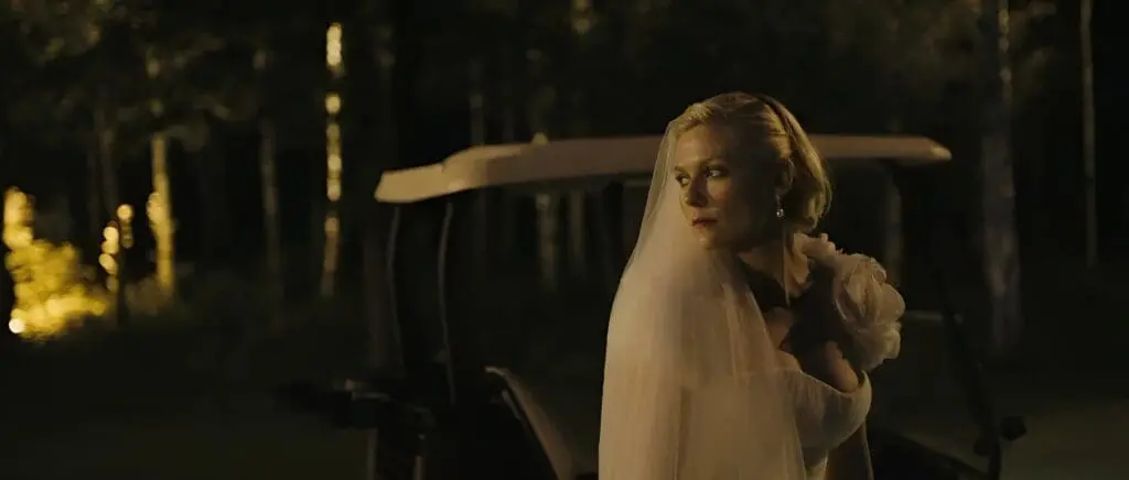 Bride in veil standing by golf cart at night