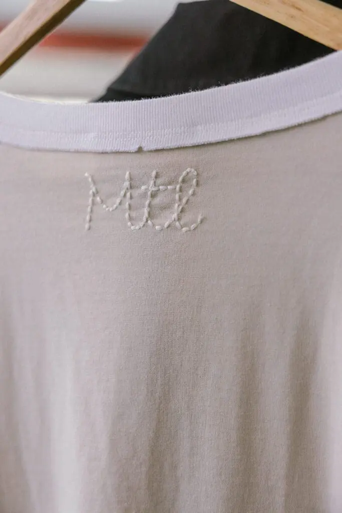 Close-up of embroidered MTL logo on beige shirt