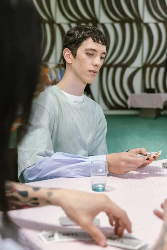 Young male model in mint green shirt playing cards