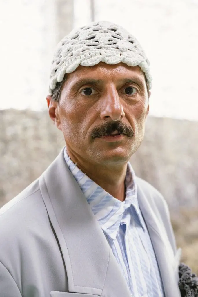 Portrait of male model in grey blazer and crochet cap