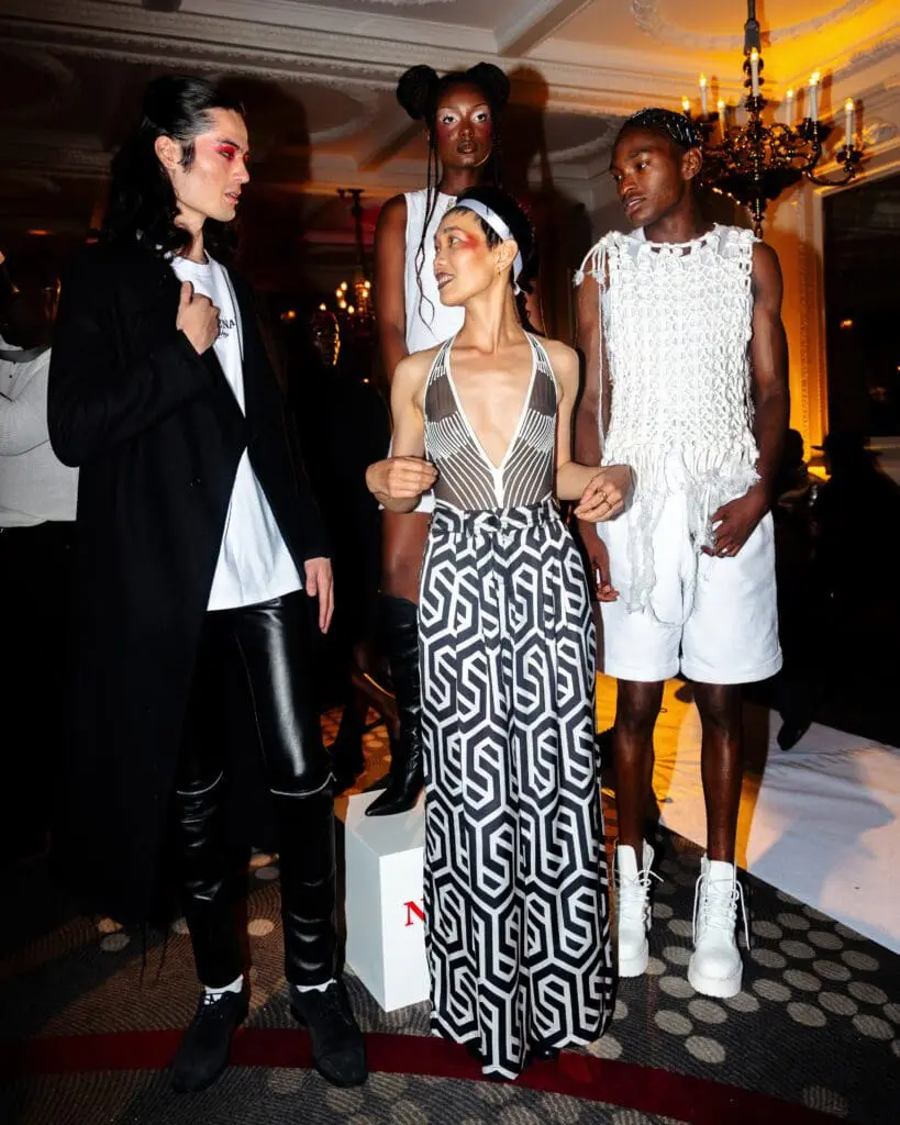 Group of models in diverse outfits from black coat to white knitwear