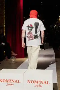 Model in white graphic t-shirt and red balaclava walking the runway