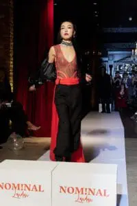 Model in sheer red swirl top and black pants with red inserts