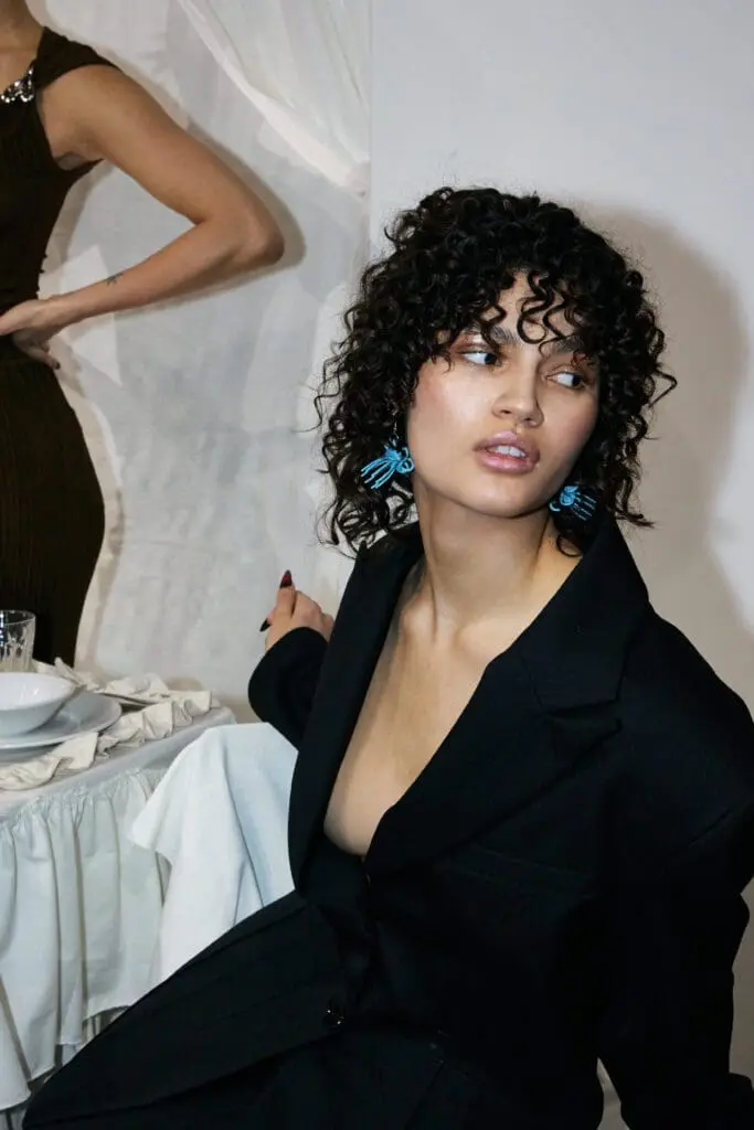 Model in black blazer with blue earrings at fashion show