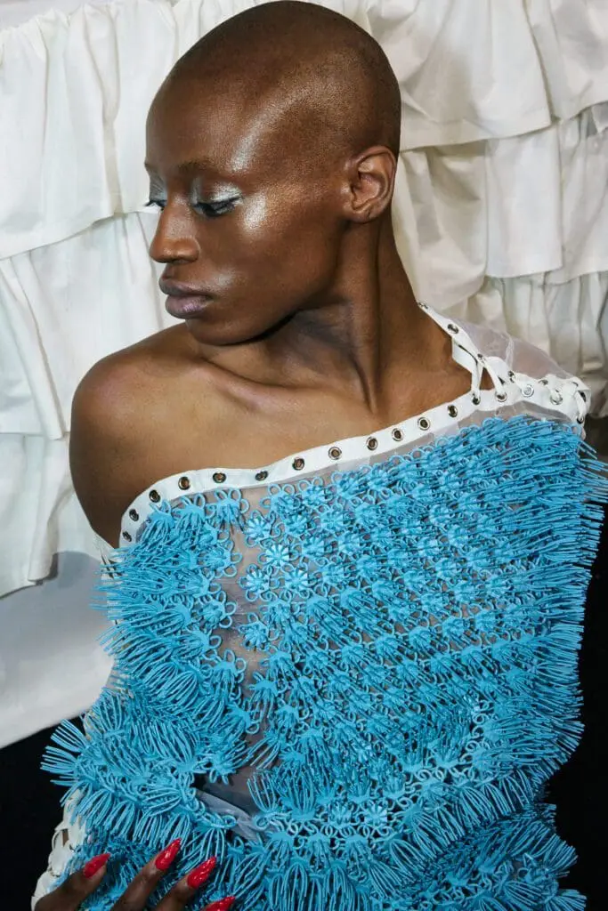 Model in sheer dress with intricate blue fringe details