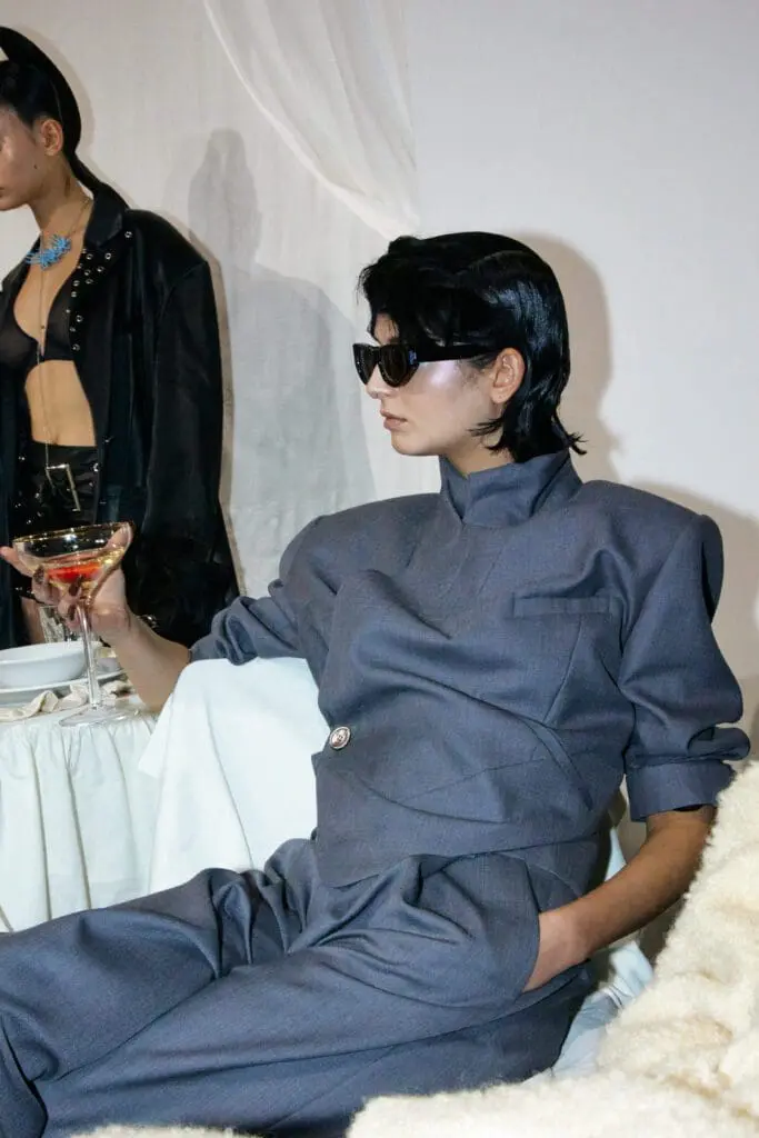 Model in grey suit with sunglasses holding cocktail glass