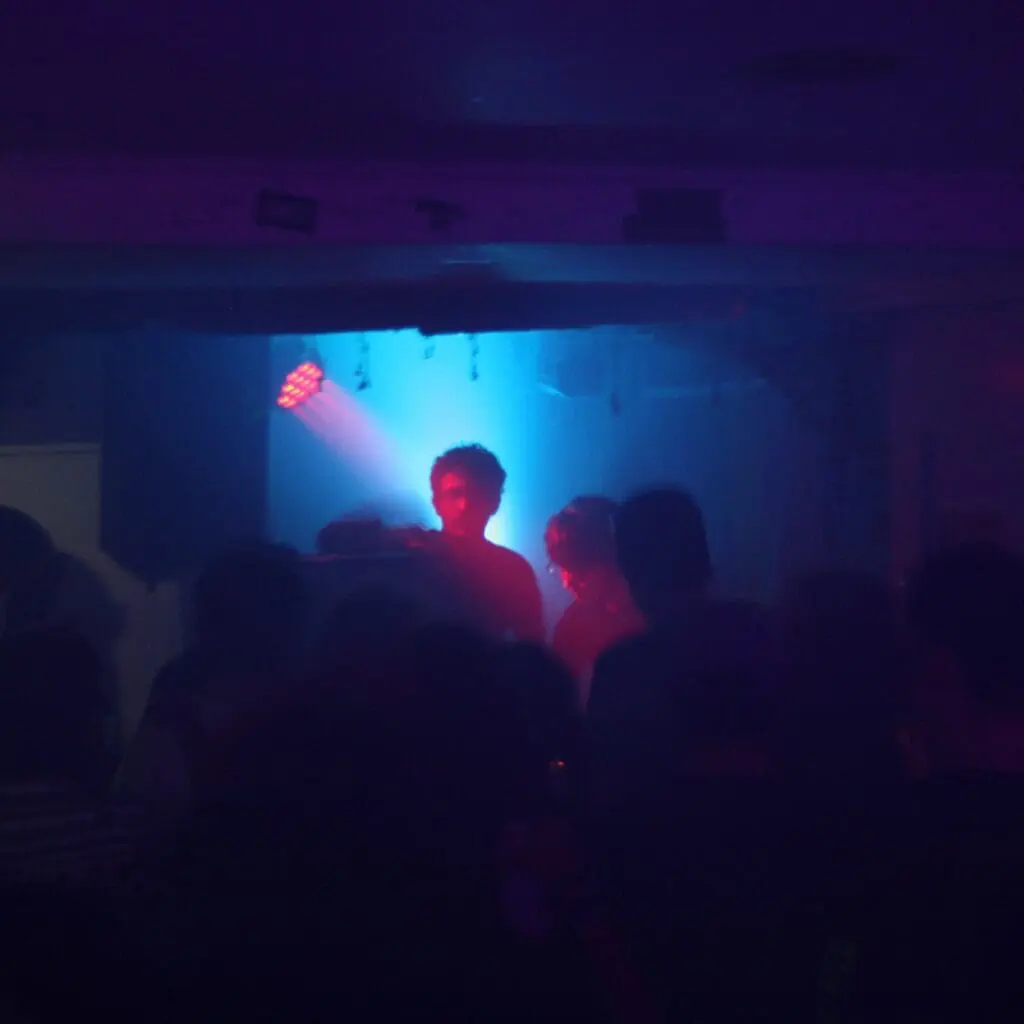 Shadowy crowd in front of stage with red and blue spotlight effects