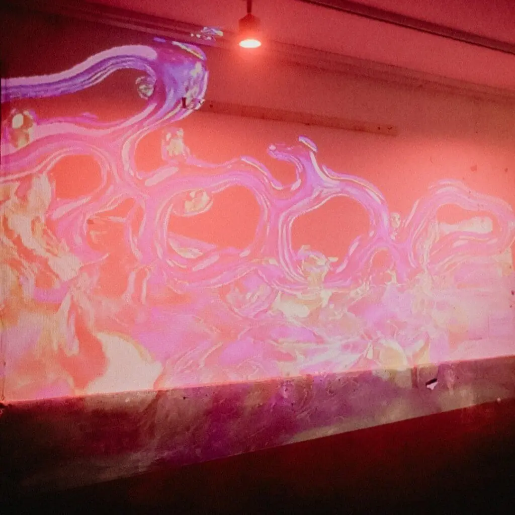 Abstract projected visuals in pink, purple, and orange on a gallery wall
