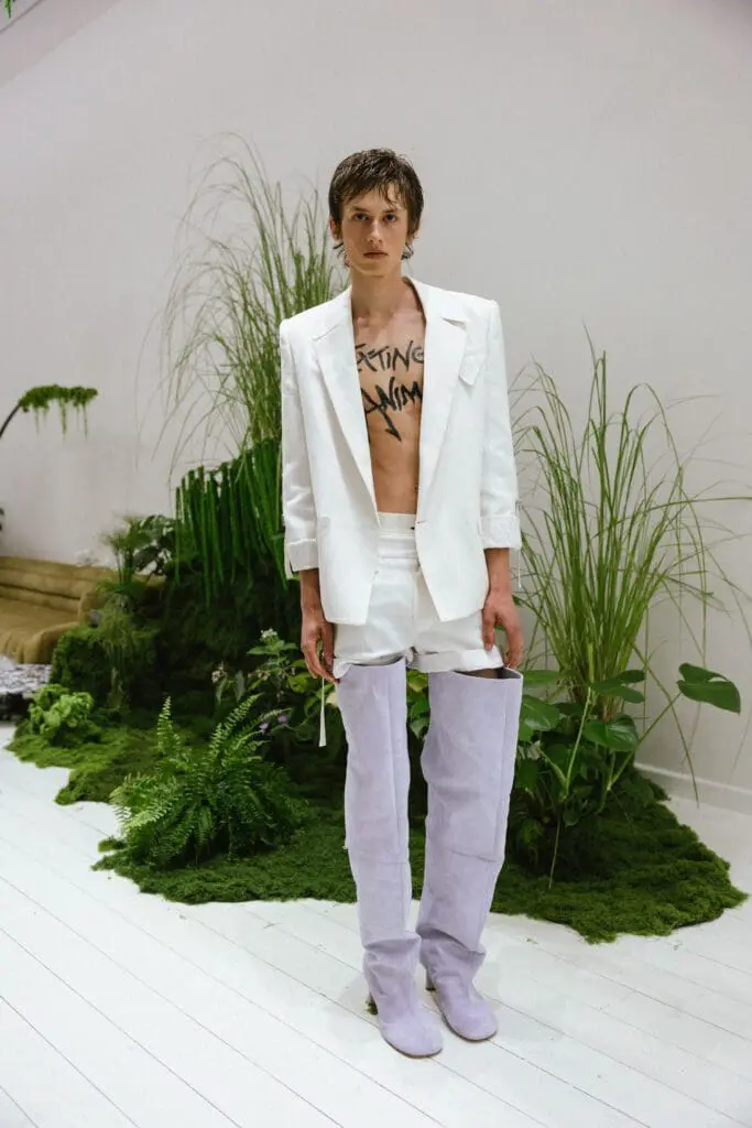 Model in white suit with Extinct Animal message SSHEENA SS26