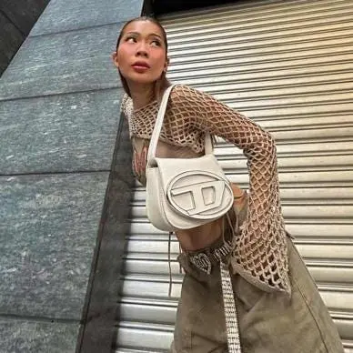 Woman in open-knit mesh top with Diesel 1DR shoulder bag and low-rise khakis