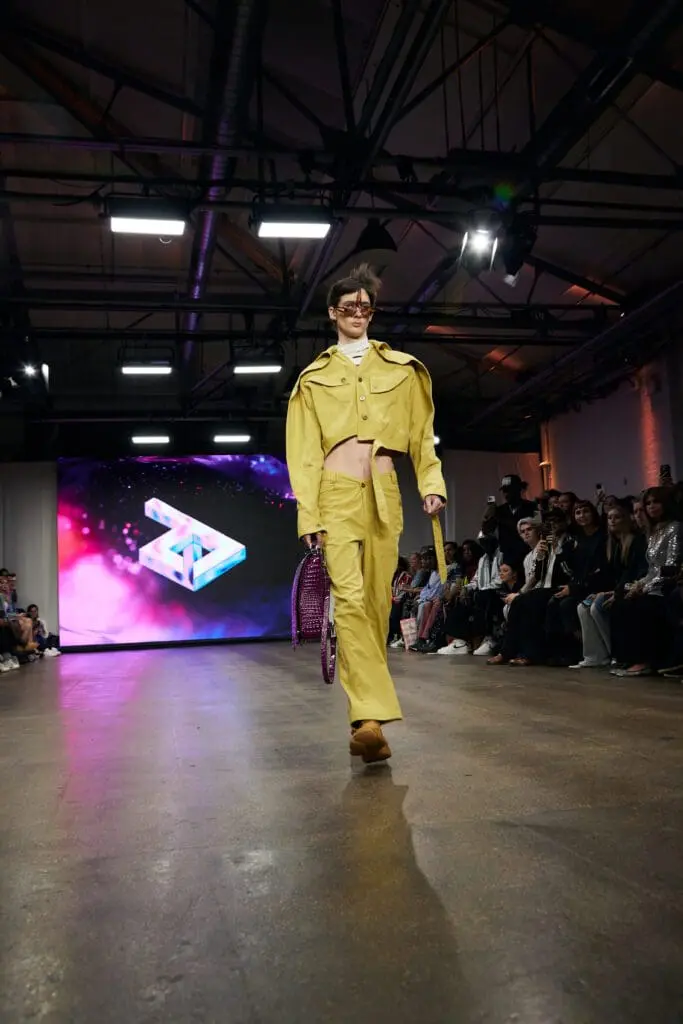 Cropped yellow jacket and trousers styled with a purple studded tote on the ZIDI runway.