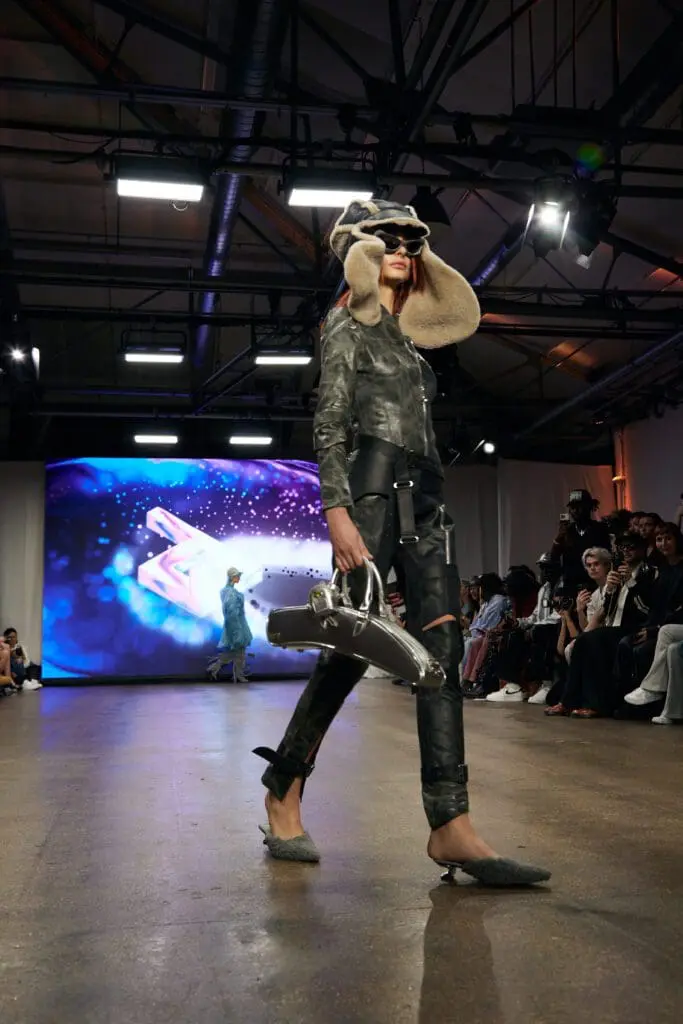 Side view of ZIDI’s leather look styled with a silver aerodynamic handbag and shearling hat.