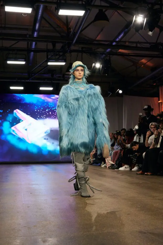 Oversized sky-blue faux-fur coat with strapped grey boots on the ZIDI runway.