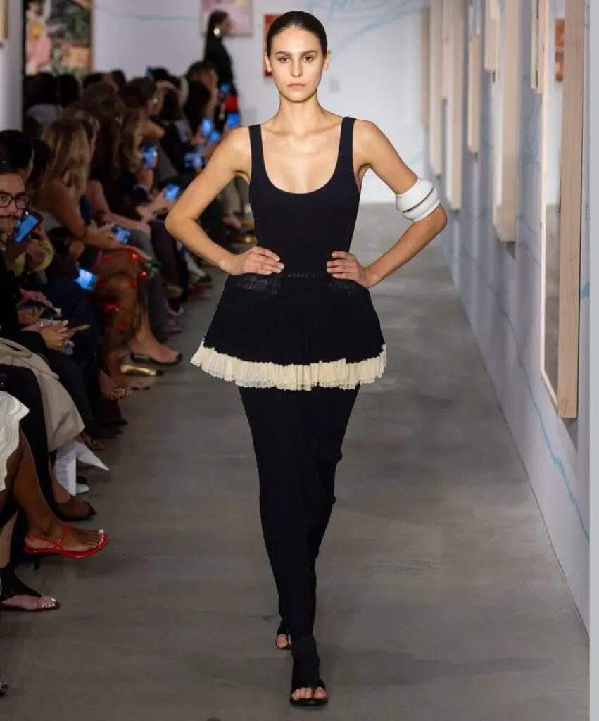 Ashlyn runway model in black dress with pleated hem