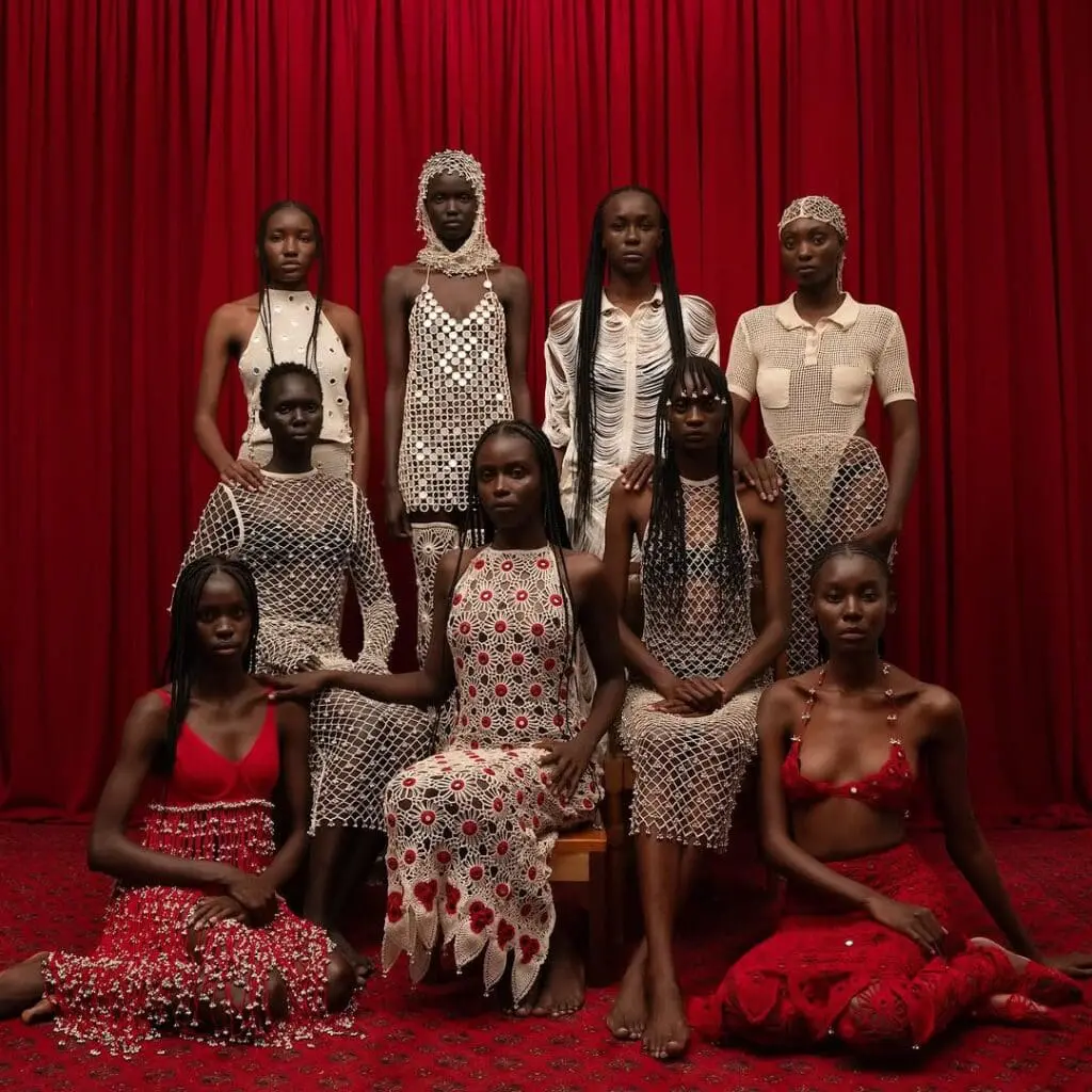 Group of Black women in patterned dresses, red backdrop