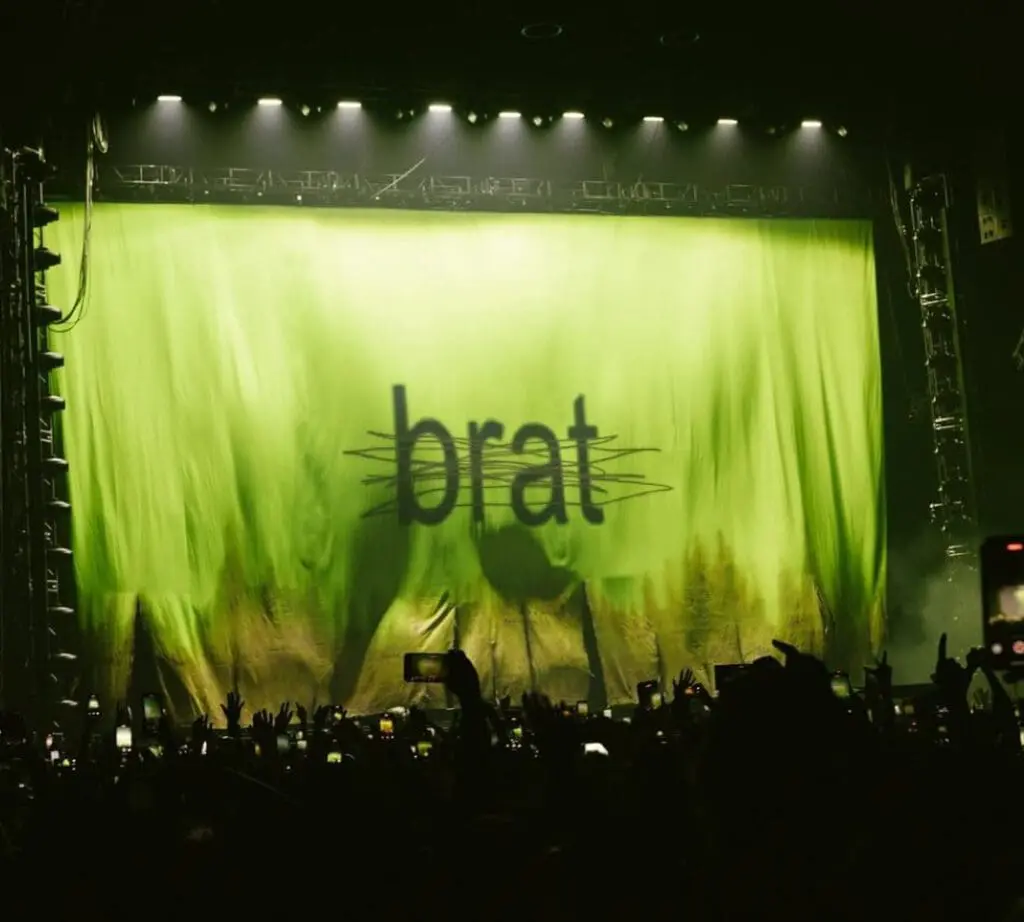 charli xcx performing on stage with brat green backdrop