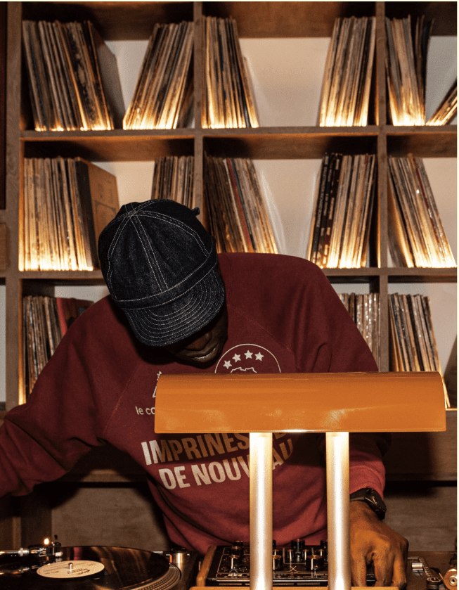 DJ mixing vinyl records under orange lamp