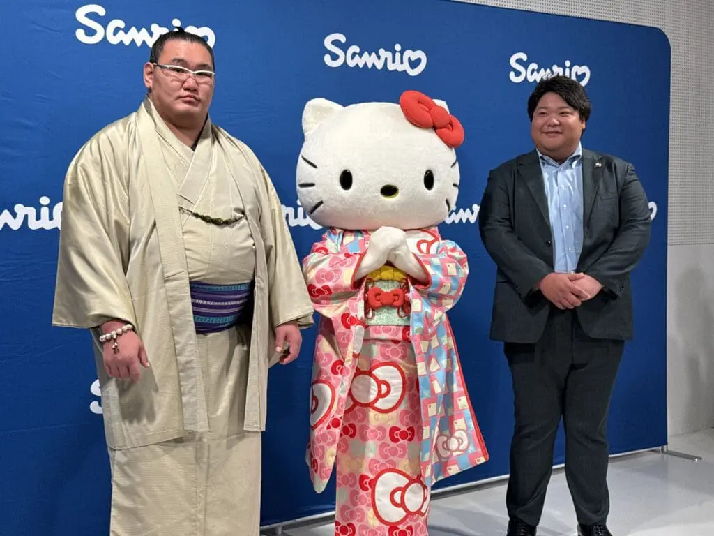 Hello Kitty stands between two sumo athletes at Sanrio event